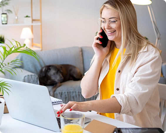 Empreendedora atendendo um cliente ao telefone enquanto acompanha a landing page no notebook