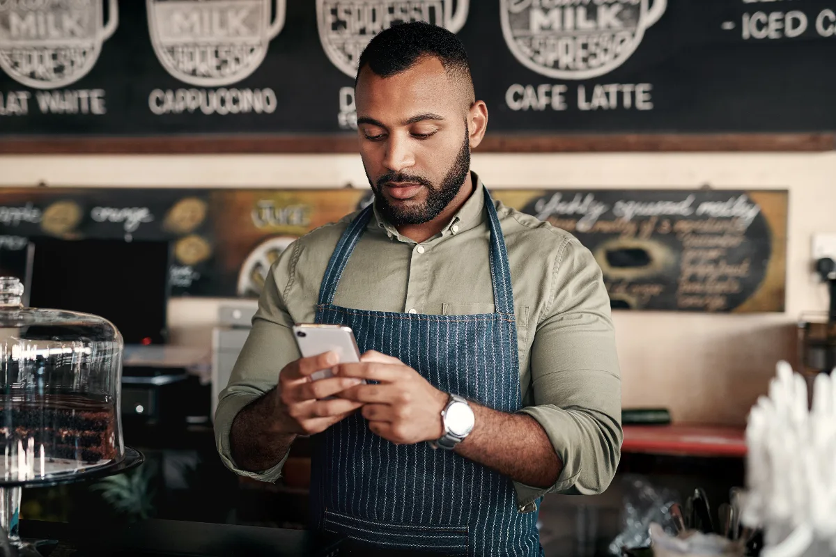 assunto de e-mail marketing: empreendedora lendo mensagem no celular em loja