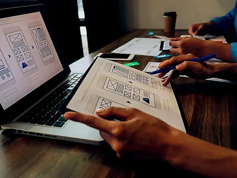 Criação de sites profissionais em São Paulo: equipe analisando wireframes em notebook e papel