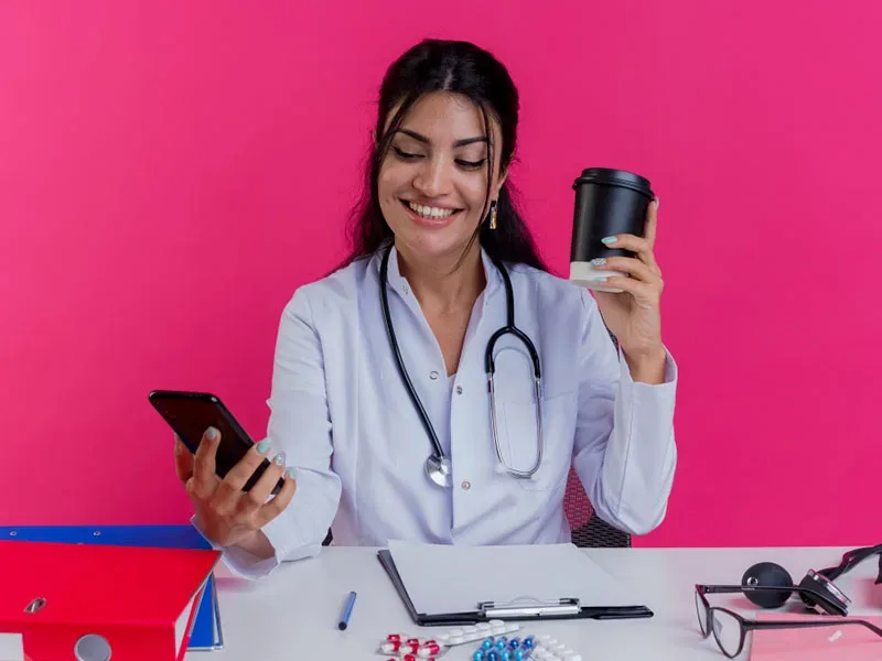 Marketing digital para clínicas: médica com jaleco usando smartphone no consultório