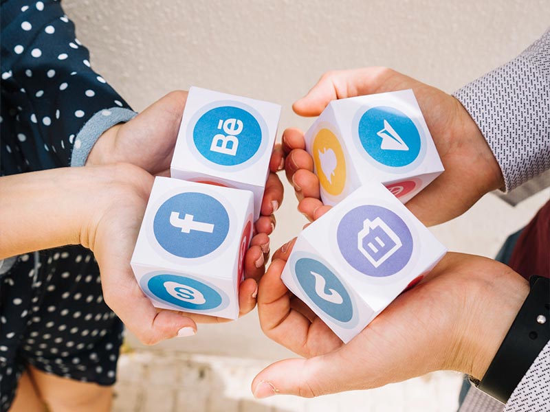 Pessoa visualizando postagens de marca e engajamento em smartphone, com ícones de várias redes sociais