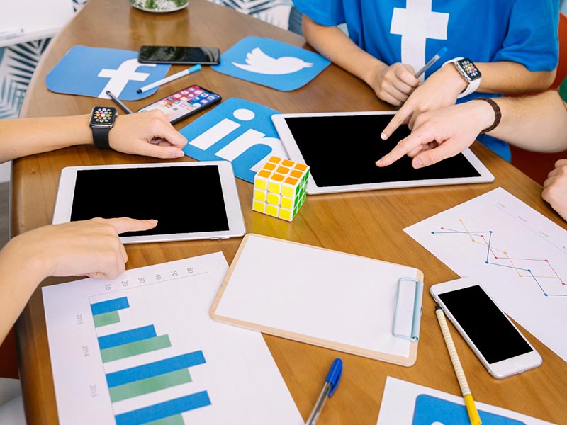 Equipe discutindo campanhas de redes sociais com gráficos e ideias em um escritório moderno